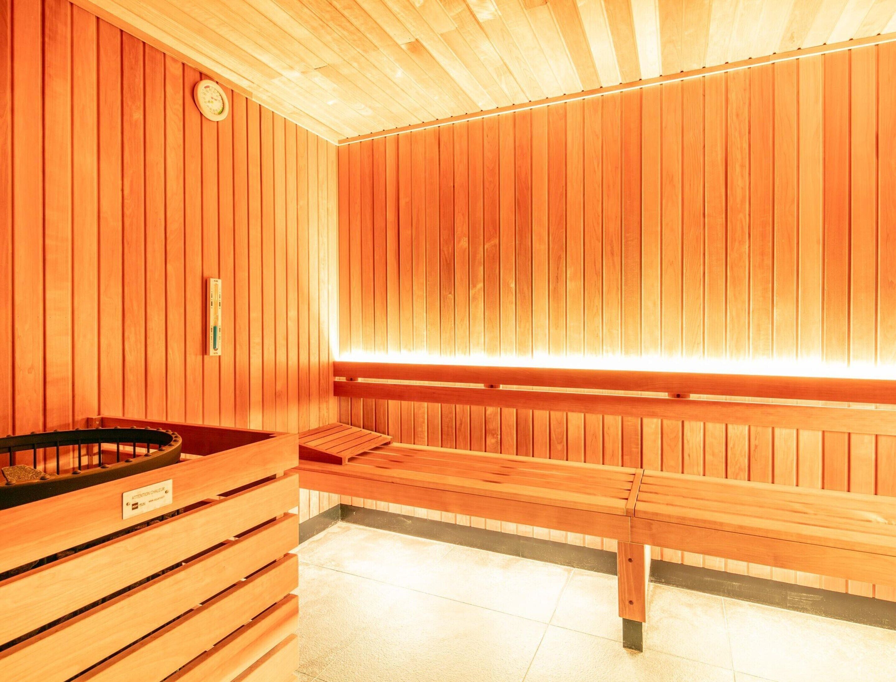 Een sauna met houten wanden, banken en een bankje met een bordje.