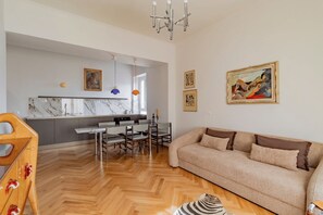 Ein modernes Wohnzimmer mit einer Couch, einem Essbereich mit Stühlen und einem Tisch sowie einer Küche mit einer Marmorarbeitsplatte.