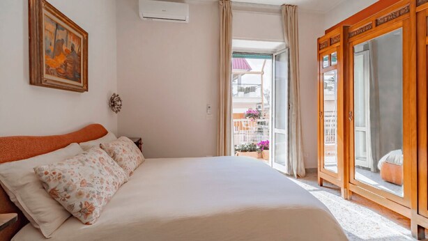 Hotellihuone, jossa on sänky, taulu, ikkuna verhoilla ja näkymä ulos.