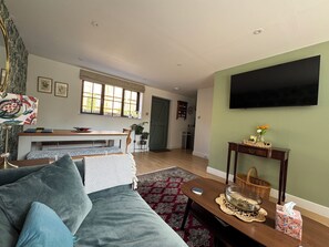 Ein Wohnzimmer mit einer Couch, einem Couchtisch, einem Fernseher und einem Essbereich mit Tisch und Stühlen.
