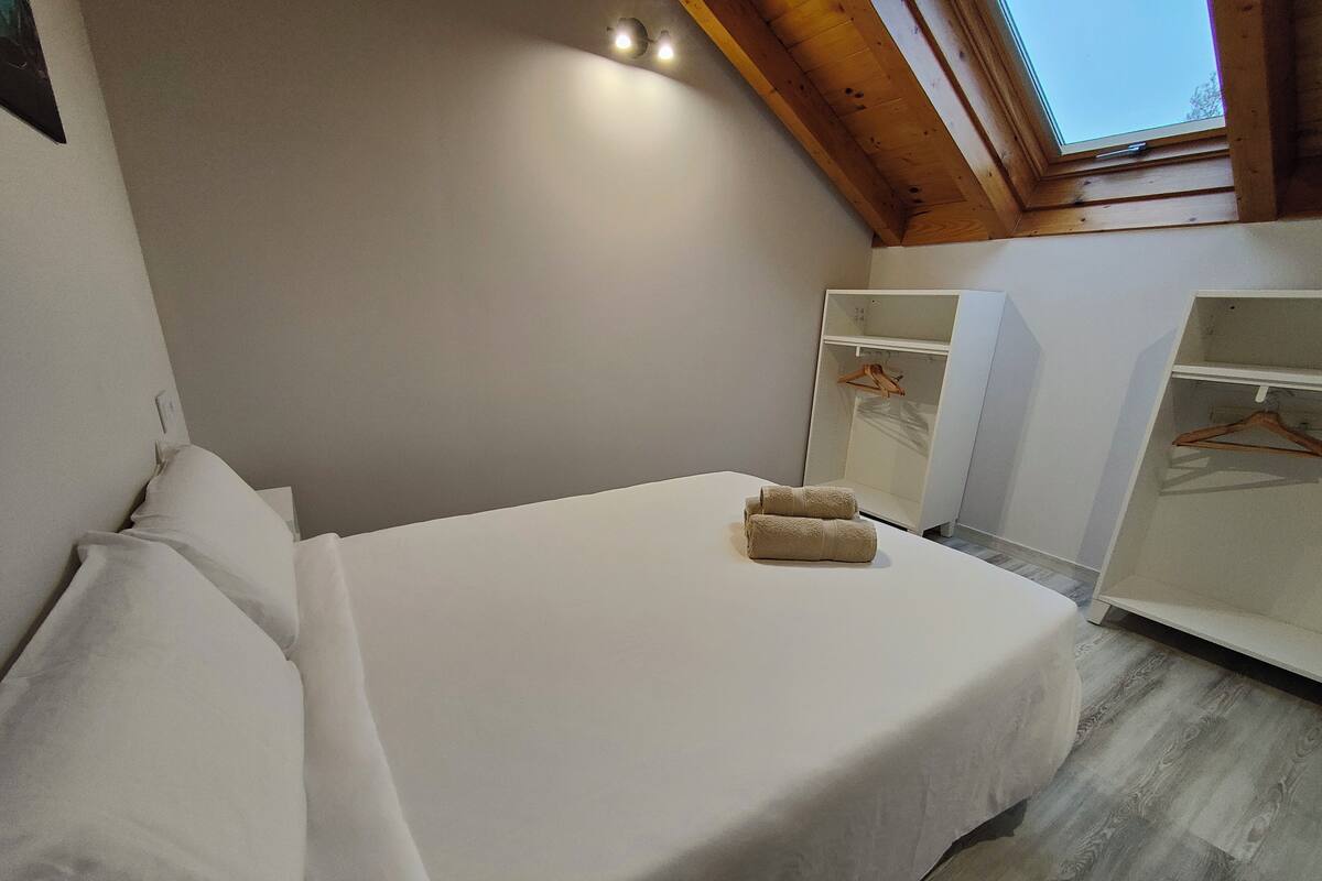 A bedroom with a bed, a wardrobe, and a skylight.