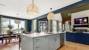 Una cucina moderna con una grande isola, luci a sospensione e una TV integrata.