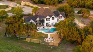 Una grande casa circondata da alberi, con piscina e giardino recintato.