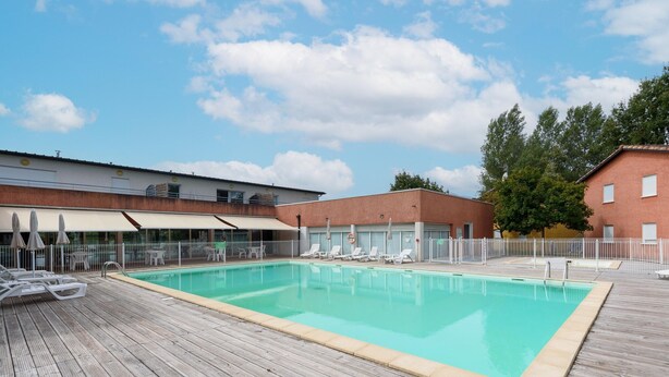A swimming pool with lounge chairs and umbrellas, surrounded by a wooden deck and a fenced area. - Accessible Vineyard Stay for Four (Rivieres)