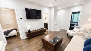Un salon moderne avec un téléviseur à écran plat, une table basse en bois, un canapé et un meuble.