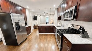 Une cuisine moderne dotée d’appareils électroménagers en acier inoxydable, de meubles en bois et d’un îlot central.