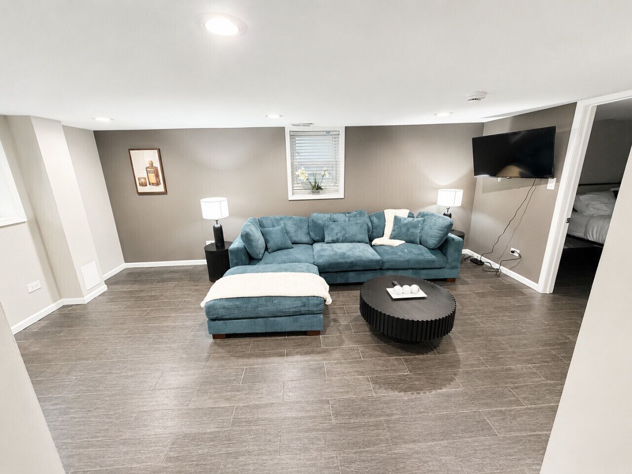 A living room with a sectional sofa, an ottoman, and a round coffee table.
