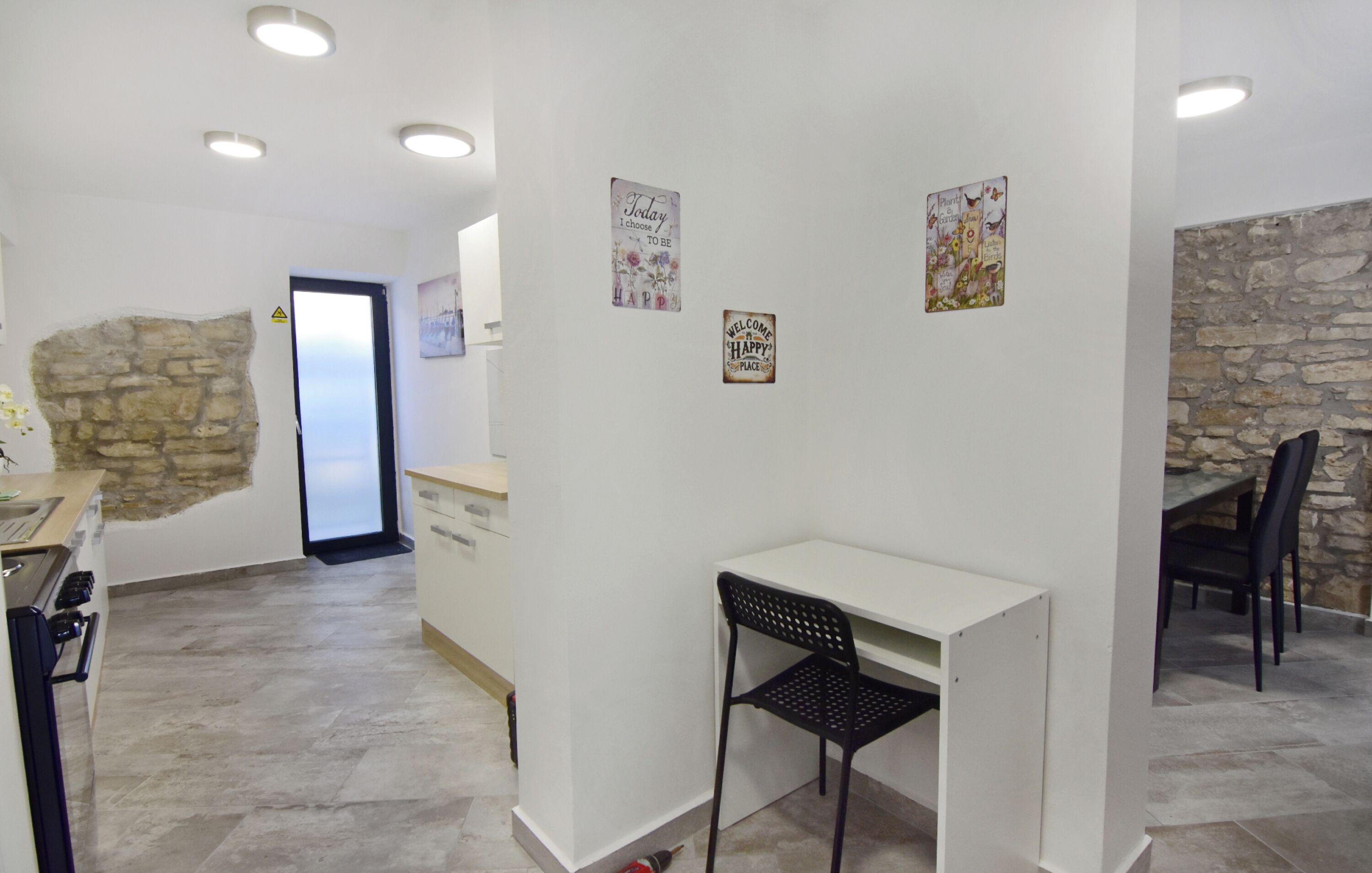 Een moderne keuken met een stenen muur, een wit aanrecht en een zwarte stoel.