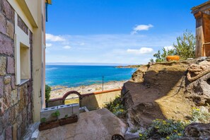 A coastal view with a stone building, a wooden structure, and a rocky ledge. - Casa Vacanza Anika Portoscuso – Apartment with Sea View and Garden (Portoscuso)