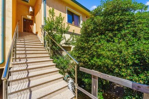 A staircase leading to a building with a wooden handrail and metal balusters. - Casa Vacanza Anika Portoscuso – Apartment with Sea View and Garden (Portoscuso)