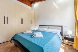 A bedroom with a bed, a nightstand, a lamp, and a wardrobe. - Casa Vacanza Anika Portoscuso – Apartment with Sea View and Garden (Portoscuso)
