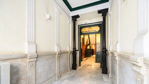 Un couloir doté d’un sol en marbre, de murs blancs et de colonnes noires.