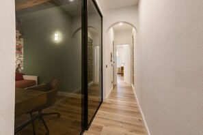 A hallway with a glass partition, a wooden floor, and a dining area with a table and chairs. - Fiammetta by MMega Homes and Villas (Florence)