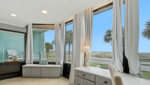 Ein Zimmer mit großem Fenster, gepolsterter Bank, Schreibtisch und Lampe.