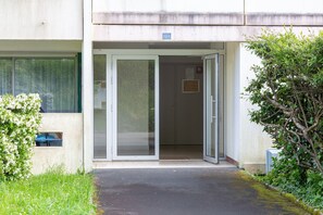 Une entrée d’immeuble avec une porte vitrée, une petite fenêtre et une plaque portant le numéro « 21 ».