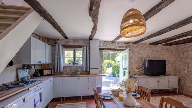 A kitchen with a dining area, stone walls, and a television.