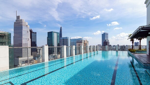Piscina infinita no terraço com vista para o horizonte urbano, arquitetura moderna e céu limpo.