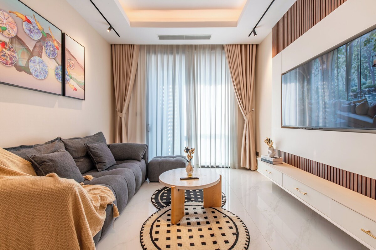 Ein modernes Wohnzimmer mit einer Couch, einem Couchtisch und einem an der Wand montierten Fernseher.