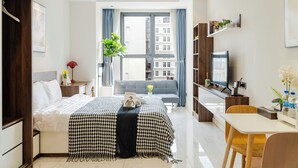 Quarto de hotel moderno com uma cama grande, uma escrivaninha, televisão e vista para a cidade.