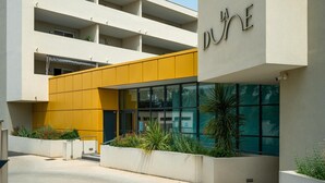 En modern byggnad med en gul fasad, flera balkonger och en skylt med texten ”LA DUNE”.
