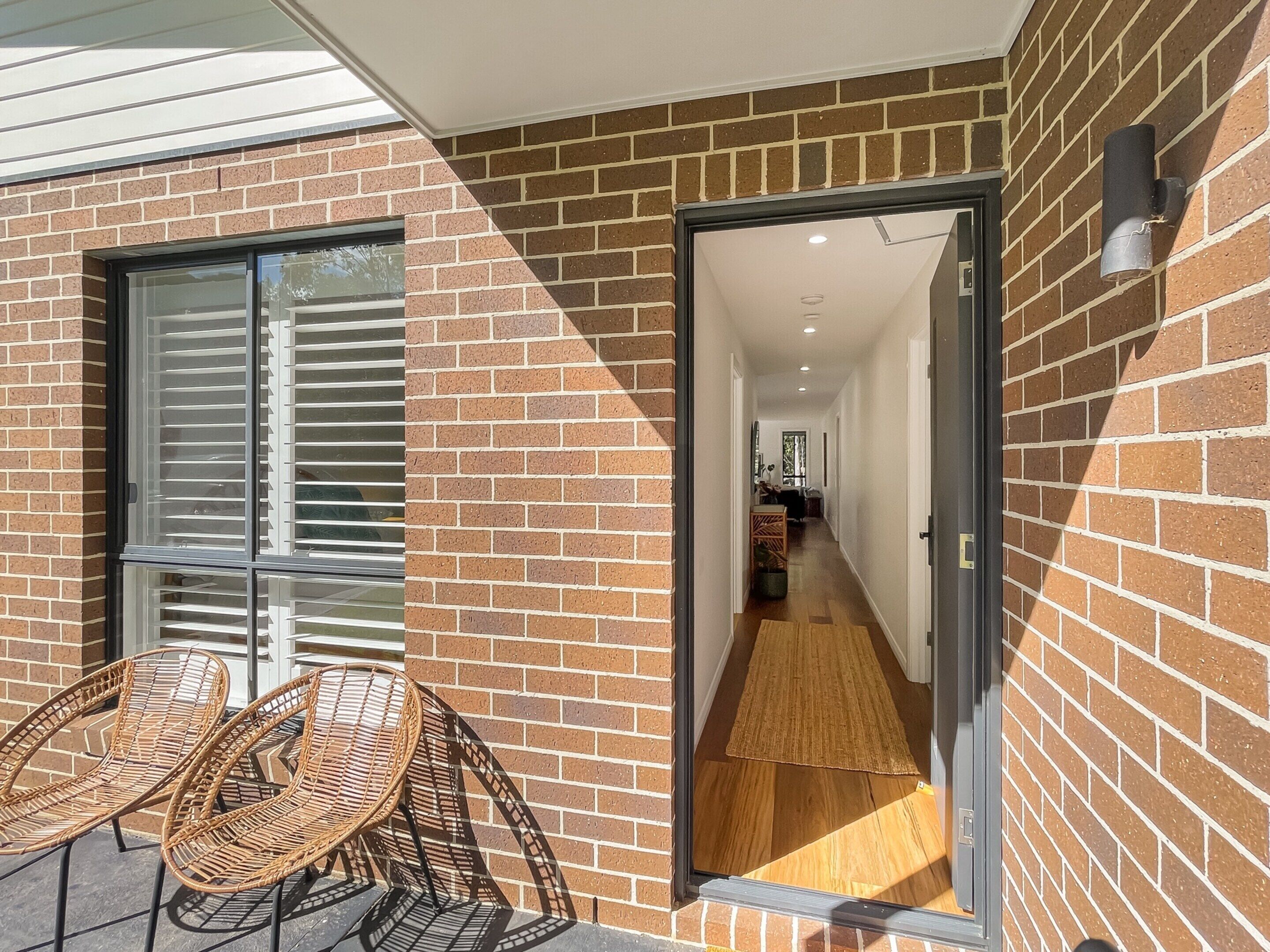 A brick exterior with a glass door leading to a hallway.