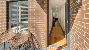 Fachada de tijolos com porta de vidro que dá para um corredor.
