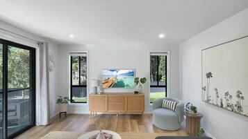 A modern living room with a wooden cabinet, a round coffee table, a grey armchair, and a large painting on the wall.