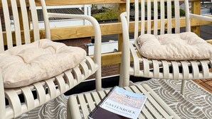 A terrace with two white chairs, a wooden bench, and a notebook on the table. - StationBeds Studio Station&citycentre (Alkmaar)