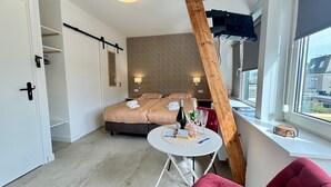 A bedroom with a bed, bedside table, and a window with a view. - StationBeds Studio Station&citycentre (Alkmaar)