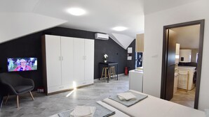 Een moderne hotelkamer met een televisie, bureau, stoel, bed en kitchenette.