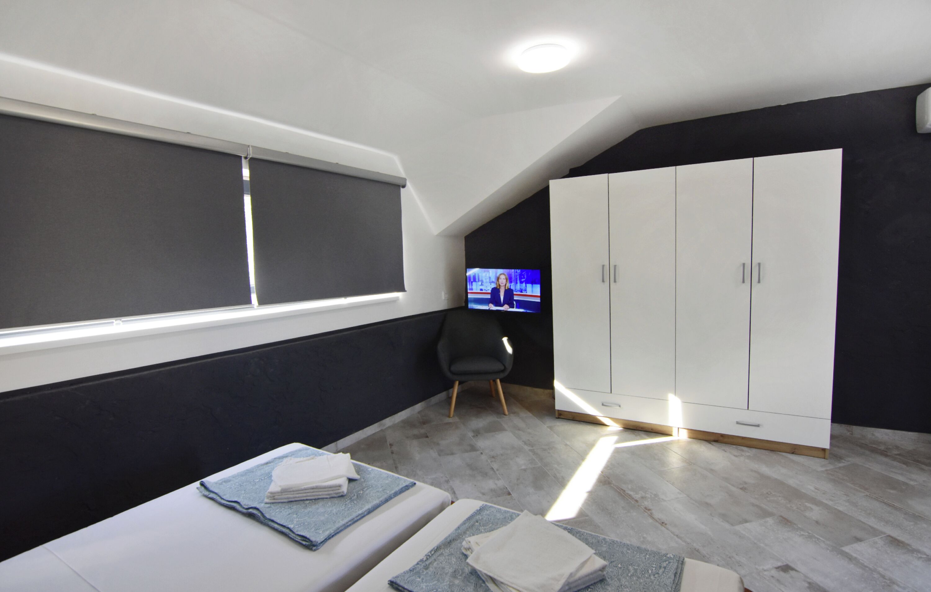 Une chambre moderne dotée d’une grande fenêtre, d’une télévision, d’une armoire et d’un lit avec des serviettes.