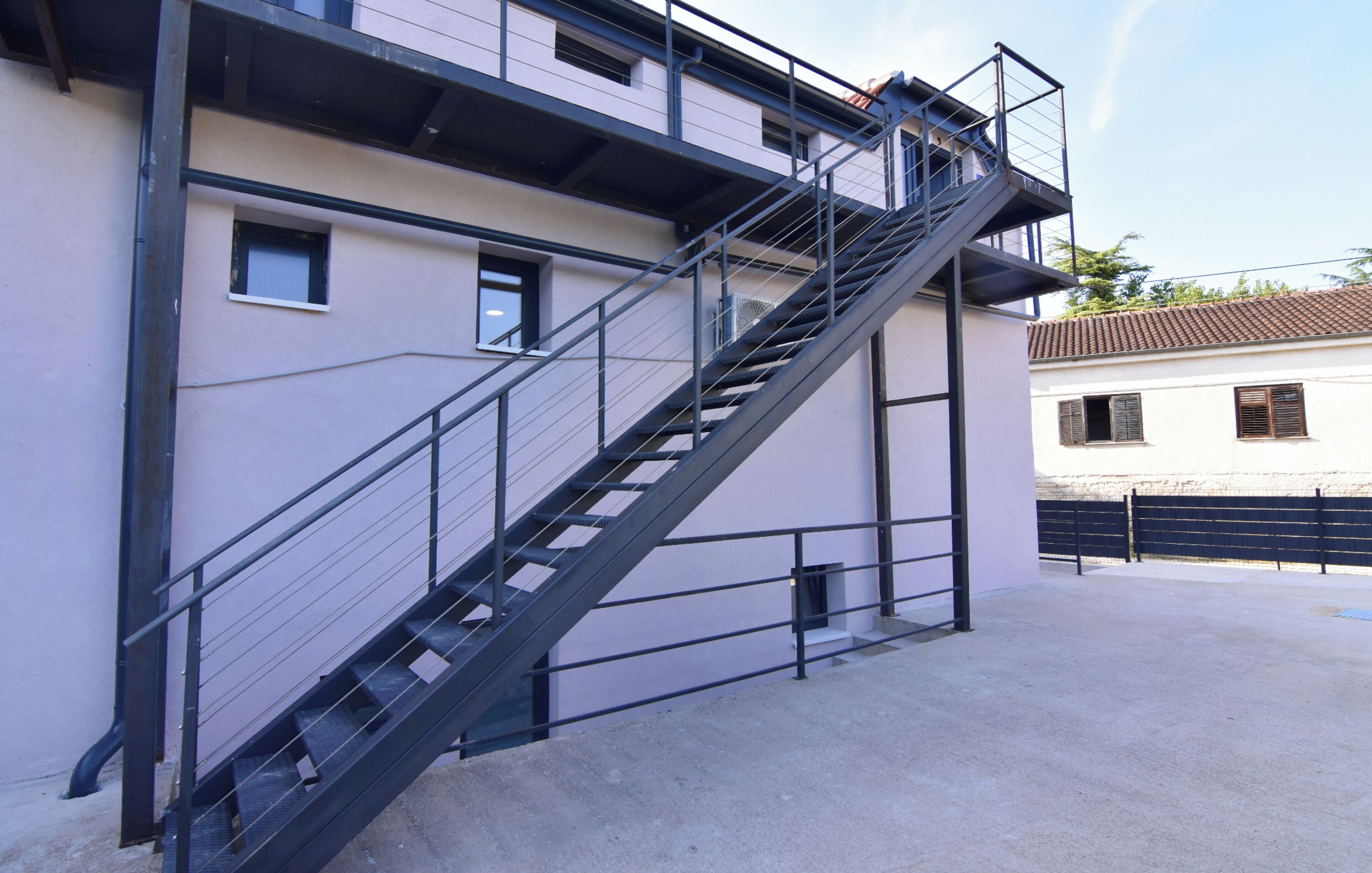 A multi-story building with a metal staircase leading to an upper level.