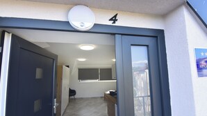 A building entrance with a dark door, a number '4' sign, a security camera, and a window with a view of bicycles outside. - Lovely Apartment for a Comfortable Stay (Buje)