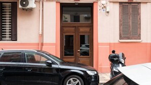 A building with a brown door, a window with shutters, and a parked car. - Almarea Suites Levante by Wonderful Italy (Bari)