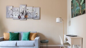 A living room with a sofa, a small round table, a desk with a chair, and a lamp. - Almarea Suites Levante by Wonderful Italy (Bari)