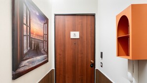 A hotel room with a wooden door, a painting on the wall, and a telephone on the wall. - Almarea Suites Levante by Wonderful Italy (Bari)