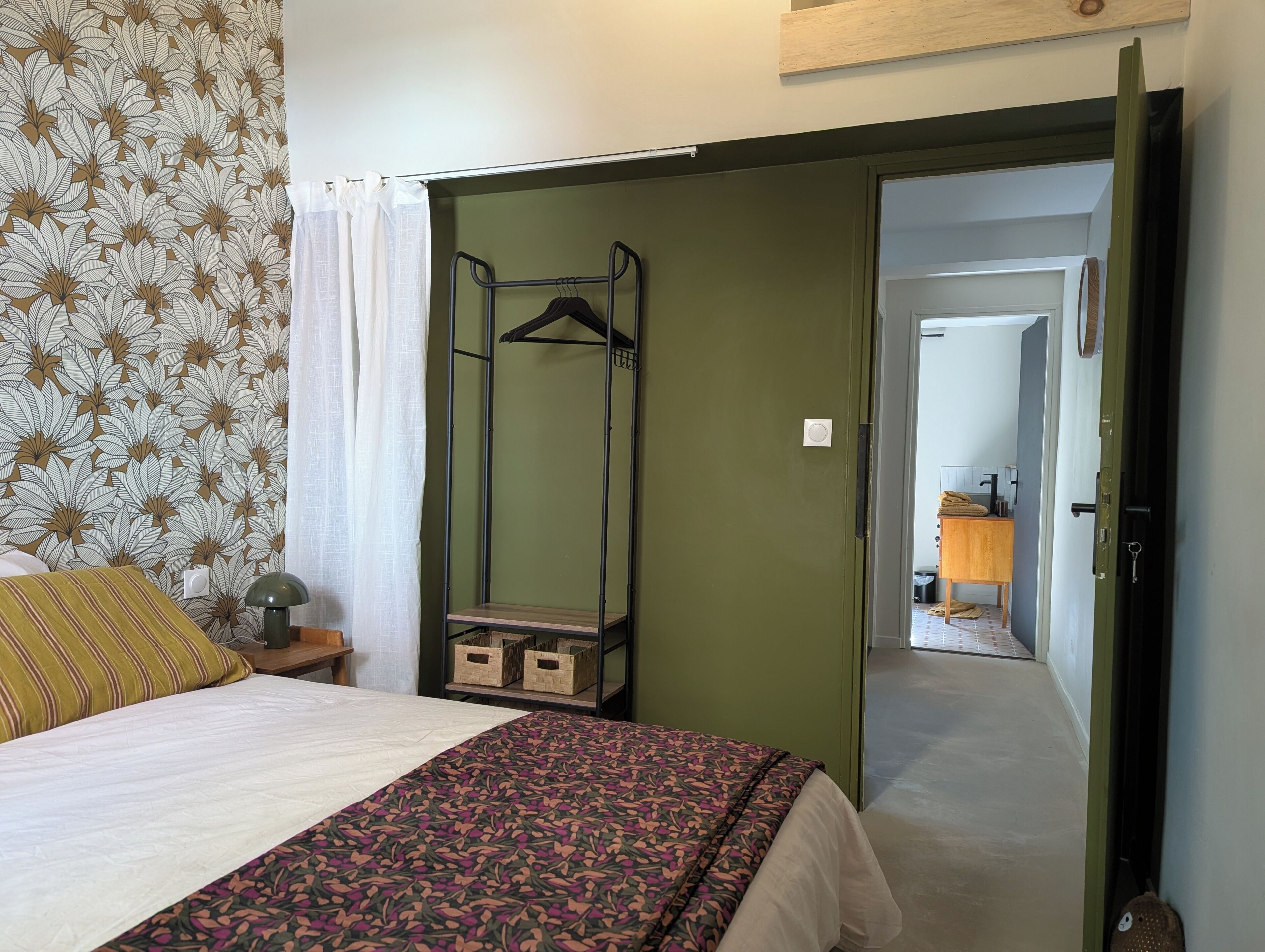 A bedroom with a bed, a hanging clothes rack, and a wardrobe.