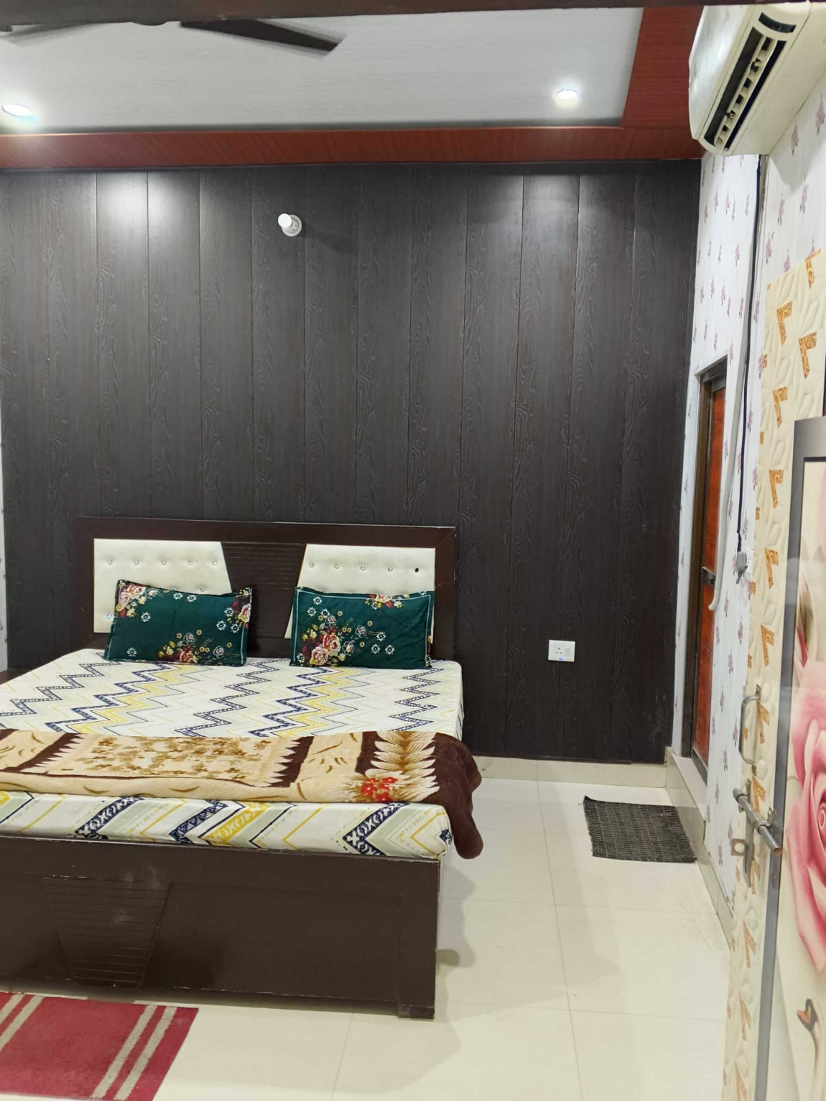 A bedroom with a bed, dark wooden walls, a ceiling fan, and an air conditioning unit.