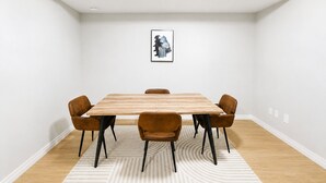 Ein Konferenzraum mit einem Holztisch, sechs braunen Stühlen, einem gemusterten Teppich und einem gerahmten Bild an der Wand.