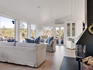 A spacious living area with a fireplace, large windows, and a view of the outdoors. - 5 Star Holiday Home in Hjalteby (Hjaelteby)