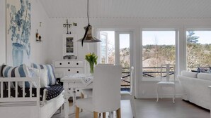 Amplia sala de estar con un sofá blanco, una mesa de comedor y vistas al exterior.