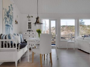 Ein geräumiges Wohnzimmer mit einem weißen Sofa, einem Esstisch und Blick ins Freie.