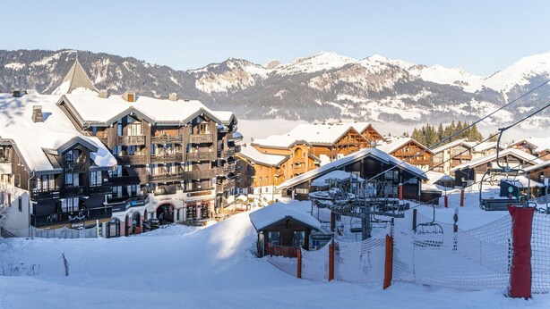 A snow-covered mountain resort with wooden buildings, ski lifts, and a clear view of snow-capped mountains. - Central Alpine Stay for 5 in Morillon (Morillon)