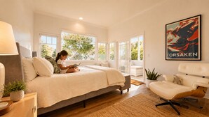 A bedroom with a bed, a reading chair, a sofa, a potted plant, and a large window. - Luxury Broad Beach Malibu spacious 3,400 sf retreat one block from the beach (Malibu)