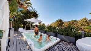 A hot tub with a wooden deck, surrounded by potted plants and a tiled patio area. - Luxury Broad Beach Malibu spacious 3,400 sf retreat one block from the beach (Malibu)