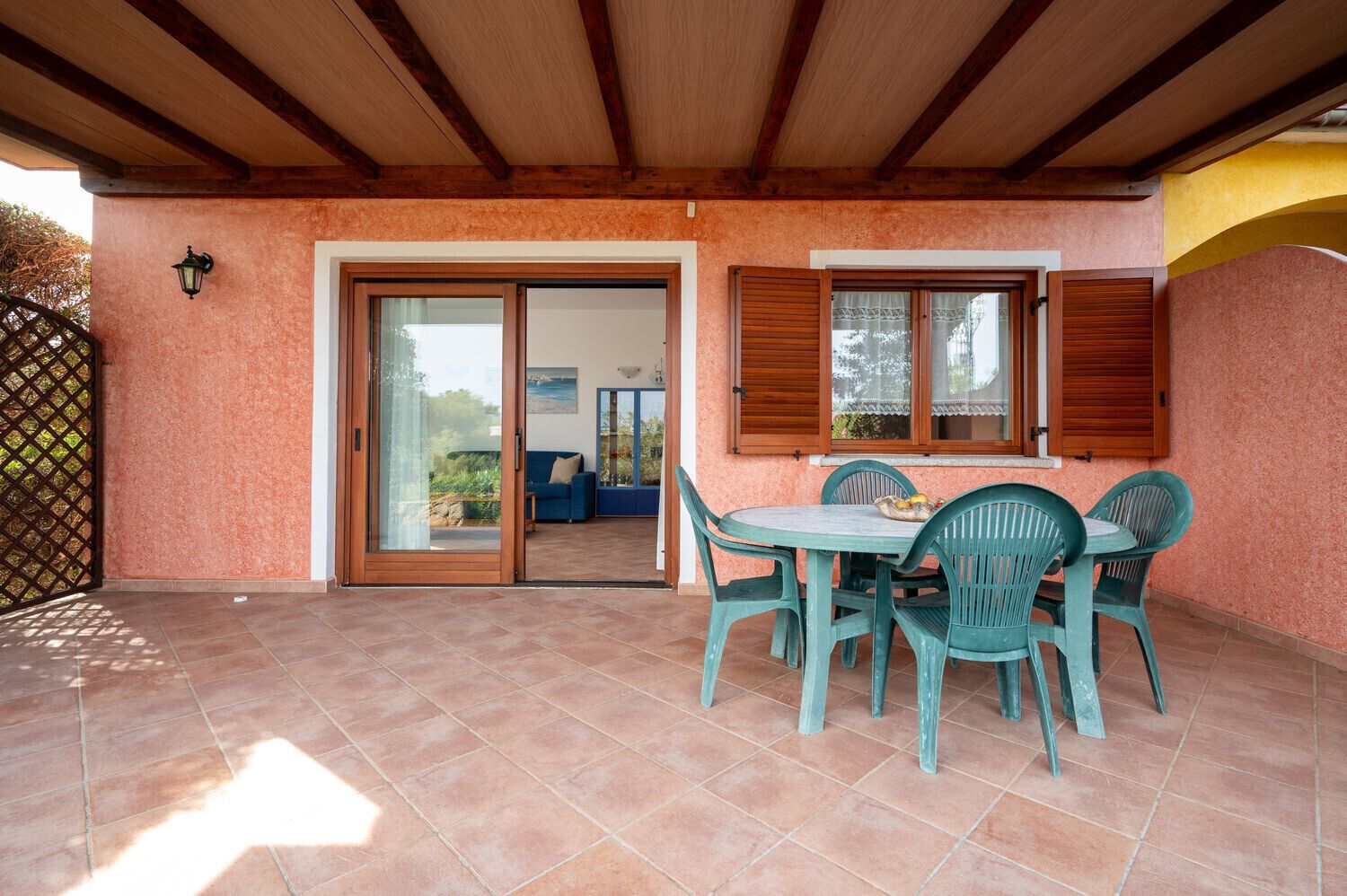 A covered patio with a table and chairs, a sliding glass door, and a view of the outdoors.