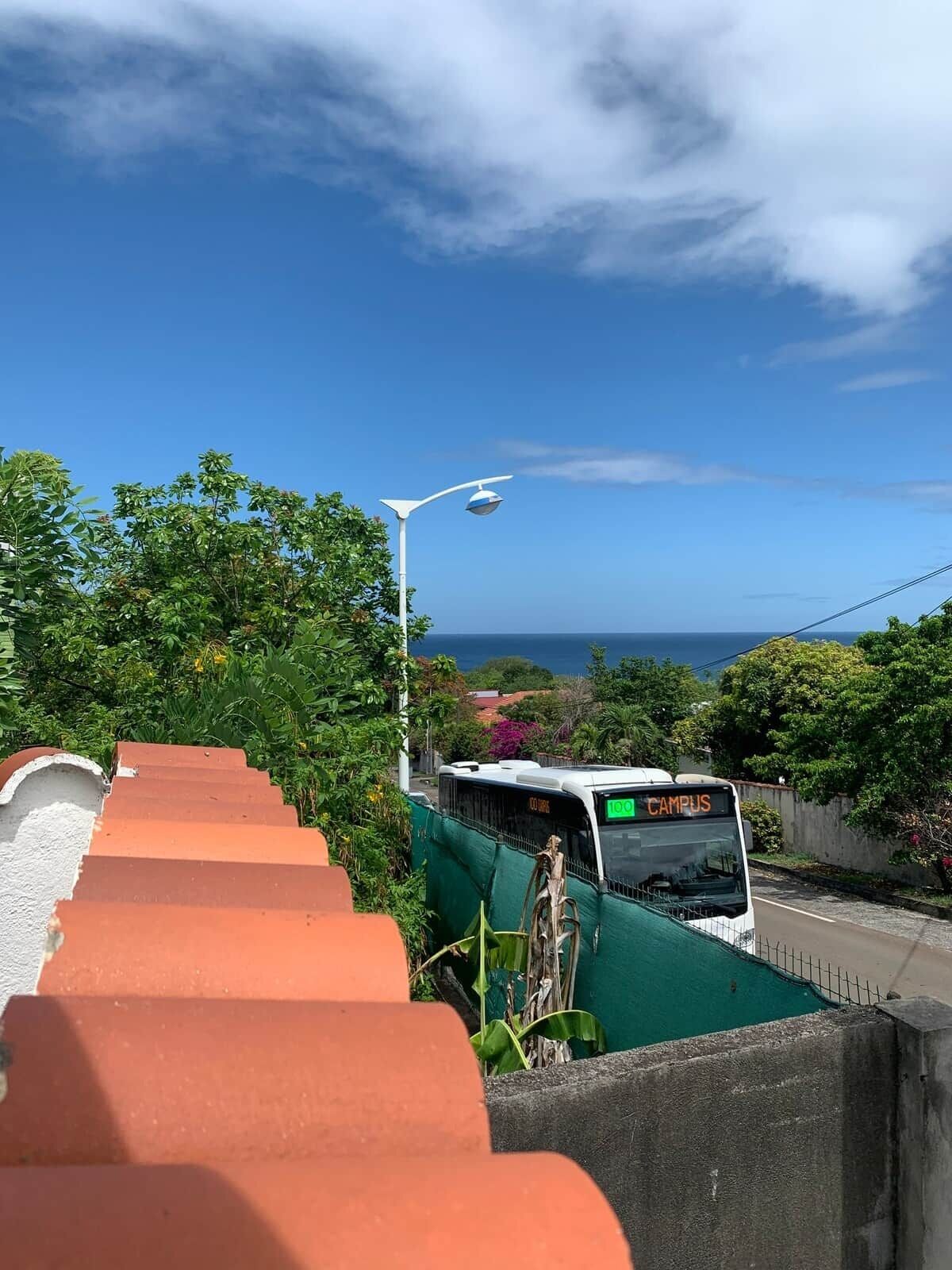 En buss med texten ”CAMPUS” på framsidan, en trappa och fri sikt över havet.