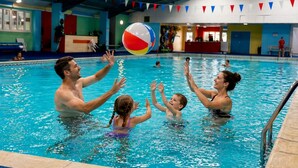 Una piscina al coperto con persone che giocano con una palla da spiaggia.