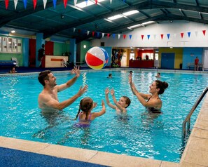 Ein Hallenbad, in dem Leute mit einem Strandball spielen.