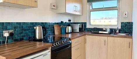 Une cuisine moderne équipée d’une cuisinière, d’un four à micro-ondes et de meubles de rangement en bois.